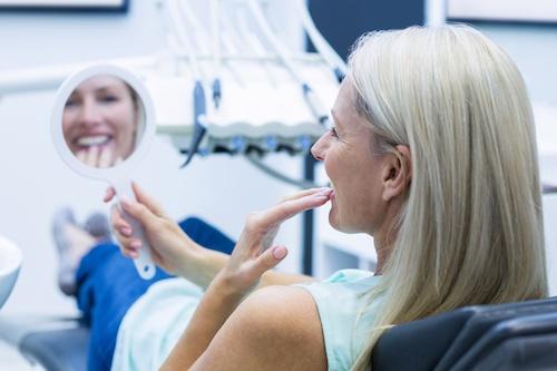 Older woman looking at her teeth after cosmetic dentistry, centerville oh