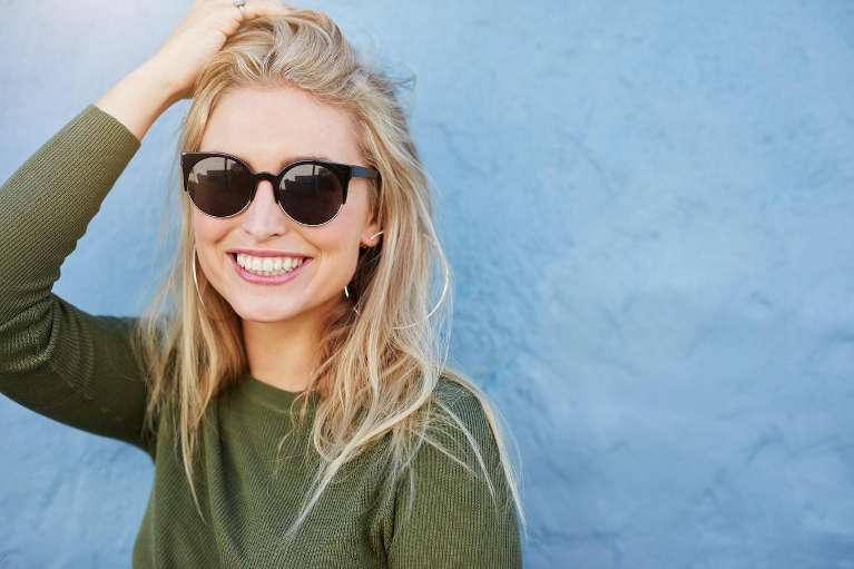Woman in sunglasses smiling after invisalign, centerville oh