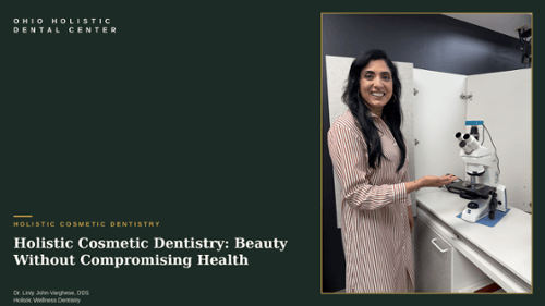 Dr. Linty John-Varghese, DDS smiling beside a microscope at Ohio Holistic Dental Center